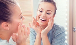 Woman examining skin in mirror