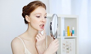 Woman looking at face in mirror