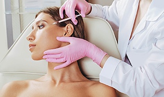 Woman receiving cosmetic injection near her eye