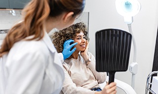 Woman looking at herself in mirror during aesthetic consultation