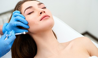 Woman relaxing while receiving facial injection