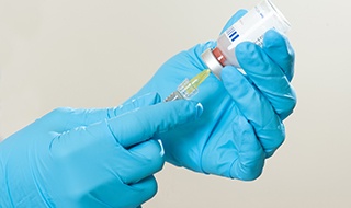 Gloved hands preparing Sculptra injection