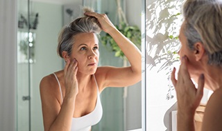 Woman looking in mirror, concerned about signs of collagen loss