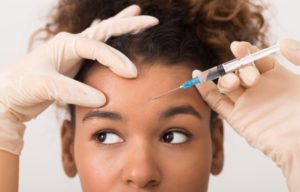 a woman receiving a Botox injection in the forehead region of her face