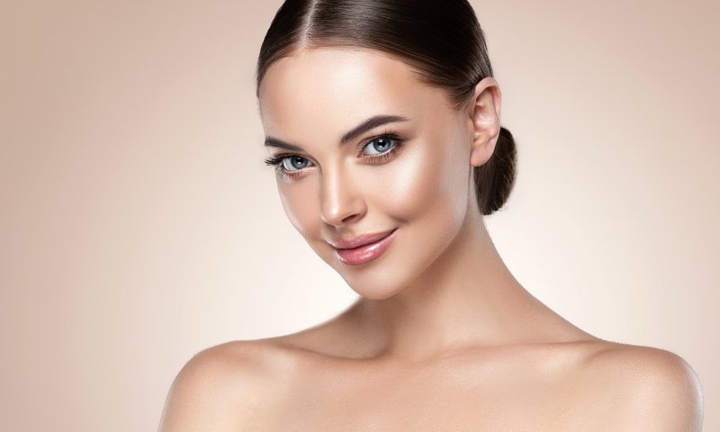 a young woman with dark hair smiling after receiving skincare treatment