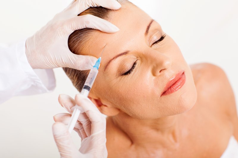 an older woman having BOTOX injected into her forehead