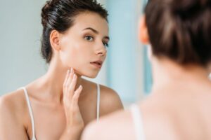 Woman looking at herself in mirror, wondering about BOTOX