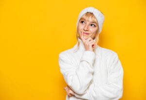 Woman in white sweater wearing curious expression 